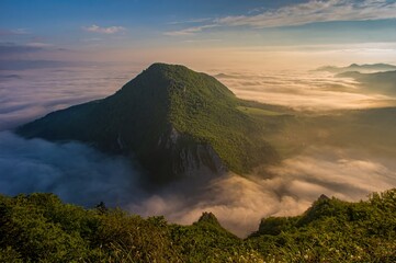 Wall Mural - Rocky, forested hill emerges from the valley in the mist. Beautiful morning in the mountain landscape with mists. Morning fog. Sulovske skaly, Velky Manin Povazie