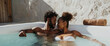 Lifestyle portrait of attractive black couple on honeymoon vacation relaxing in hot tub pool at luxury resort spa