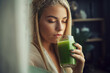 vegan woman drinking green juice from a glass