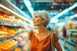 An elderly woman gazes at the fruit selection in the fresh produce aisle of a supermarket