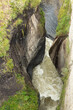 turbulent river flowing through a narrow gorge with lush vegetation