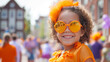 A smiling happy girl in orange clothes and sunglasses in Amsterdam during the King's Day national Dutch holiday or Holland football team support. Kingsday celebration in the Netherlands. Copy space