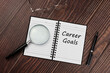 Career goals text on notepad flat lay and magnifying glass