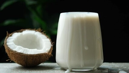 Wall Mural - Coconut slices falling into a glass of coconut milk slow motion