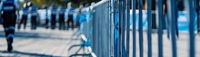 Close-up On Crowd Control Barriers At An Outdoor Event, Security Personnel In The Background, Safety First