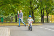 Happy family father teaches child daughter to ride public bike on one of traffic playground, Prague in Czech republic