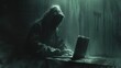 A shadowy figure sits in a dark room, obscured by a hood, their fingers dancing across a laptop keyboard.