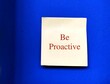 Yellow note stick on blue wall with text written BE PROACTIVE , different traits - one focuses on eliminating problems before happened and one approach is based on responding to events after they have