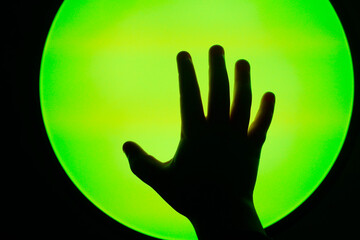 The shape of a hand reaching towards a colored light