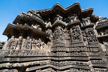 Poster - Low angle view of stone carvings of Hindu deities on the walls of the ancient Hoysaleshwara temple in Halebidu.