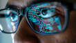 A close-up view of a mans face wearing glasses with reflections of code visible in the lenses.