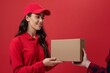 Female courier with parcels on red background. A woman hands a parcel to a customer. Delivery