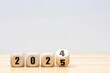 © MAITREE - Wooden 2024 to 2025 new year white background. Word 2024 - 2025 wood cube on wooden desk for copy space.