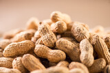 Fototapeta Przestrzenne - Peanuts. Unshelled nuts close up, over beige background. Roasted pile of peanuts in shell. Organic vegan, vegetarian food. Healthy nutrition concept.