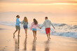 © Monkey Business - Rear View Of Couple With Friends In Casual Clothing On Vacation Running Along Beach Holding Hands