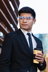 Businessman standing and drinking take away coffee near business center