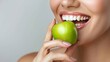 portrait of smiling beautiful woman with white healthy teeth eating green apple on white background, look like as photo