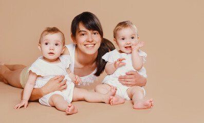 Happy cheerful smiling young mother holding baby on brown background