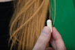 Kobieta trzyma kapsułkę z witaminami na mocne włosy przy swoich blond włosach 