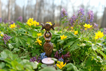 amulet of Triple Goddess with candle on floral meadow, natural background. Symbol of the Triune Moon. esoteric ritual for Beltane. witch, wiccan spiritual practice for relax, harmony