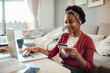 © Davor - African American woman online shopping with credit card and laptop at home