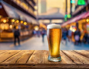 Beer glass on old wooden table top with a blurred Shopping Mall scene in the street