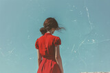 Fototapeta  - Woman in red dress looking out over clear blue sky