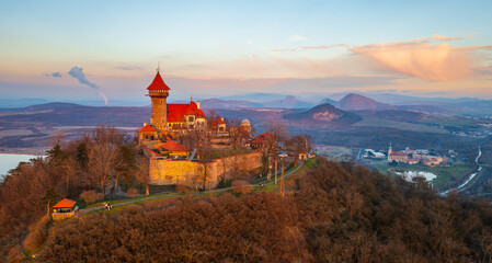 Neo-Gothic castle Hněvín at sunset. Dominant of the city of Most. Taken by drone. Lake Most and the České Středohoří can be seen in the background