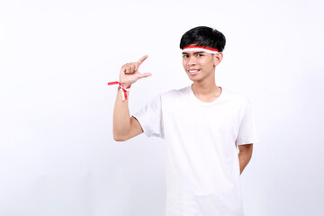 Young asian boy with red white ribbon celebrating Indonesia independence day while holding something on his fingers