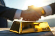 Gold bar on the table and businessman handshake, Investing or trading and exchanging gold both domestically and internationally, demand and supply on gold