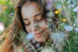 Fototapeta Paryż - Portrait of beautiful young long-haired woman lying in park and smelling flowers