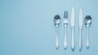 A minimalist arrangement of silverware on a pristine solid color tabletop