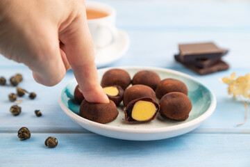 Wall Mural - Japanese rice chocolate mochi filled with cream with hand on blue wooden. side view, selective focus.