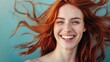 A young woman with flowing red hair and freckles smiles brightly against a blue background, her joy contagious.