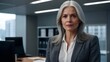 © Mads - experienced elderly executive business woman with long grey hair and formal clothing stand in office.