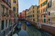 Typical narrow canal surrounded by buildings with boat in Venice, Veneto, Italy