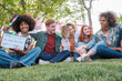 © Ivan - Group of friends sitting on the grass enjoying together in the park. Concept: friendship, fun