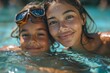 Sibling bond captured as they smile closely together in sunlit water wearing swim goggles