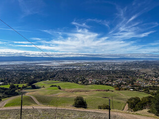 Canvas Print - a road near a grassy hill near a mountain with the view of a city below