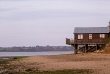 A Log Cabin On A Sandy Beach At Low Tide On The British Coastline, Image Shows The Raised Wooden Structure On Legs On A Beautiful Scenic Beach 
