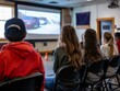 © CG Design - A group of teens looking at a wall projector during a driver's ed lecture