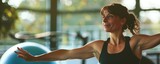 Fototapeta  - Woman performing warrior yoga pose in fitness class. Indoor workout and wellness concept with place for text.