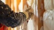 Construction worker applying spray foam insulation between wall studs