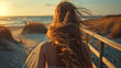 Back view portrait of lonely girl walking on a boardwalk in beach at evening with warm sunset