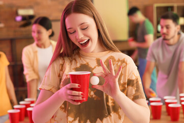 Wall Mural - Young woman with cup and ball for beer pong at party