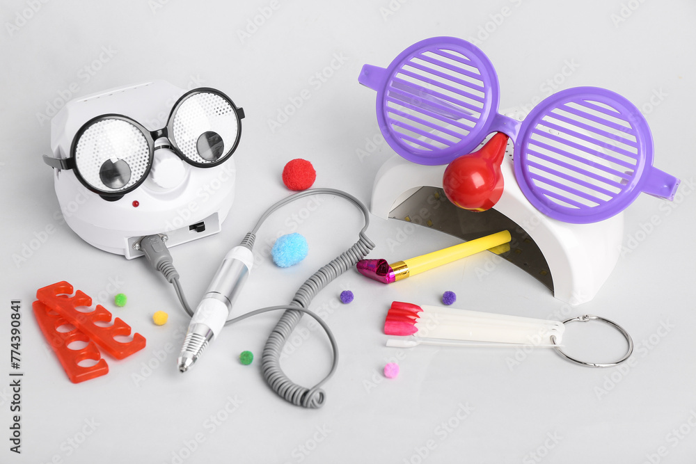 Manicure equipment and party decor on light background. April Fool's Day celebration