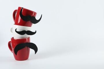 Wall Mural - Cups with fake mustaches on light background, space for text