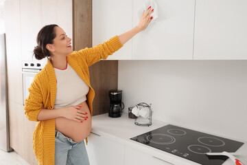 Canvas Print - Young pregnant woman cleaning cupboard in kitchen