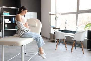 Poster - Young pregnant woman with medical patch after vaccination sitting on couch in clinic