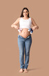 © Pixel-Shot - Young pregnant woman with baby booties on brown background